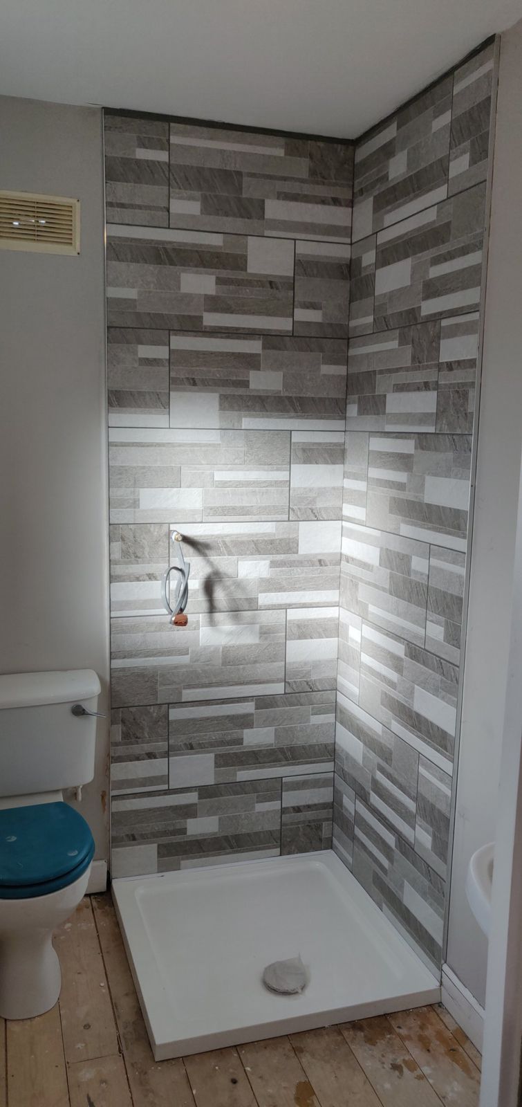 Shower walls tiled in grey split-face effect tiles