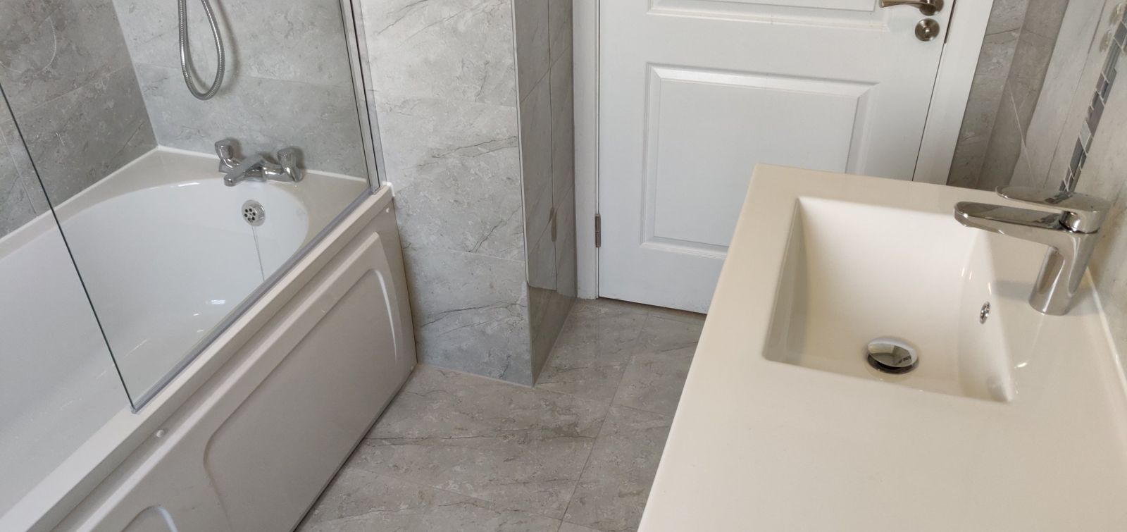 New-build bathroom with bath, glass screen and white vanity unit