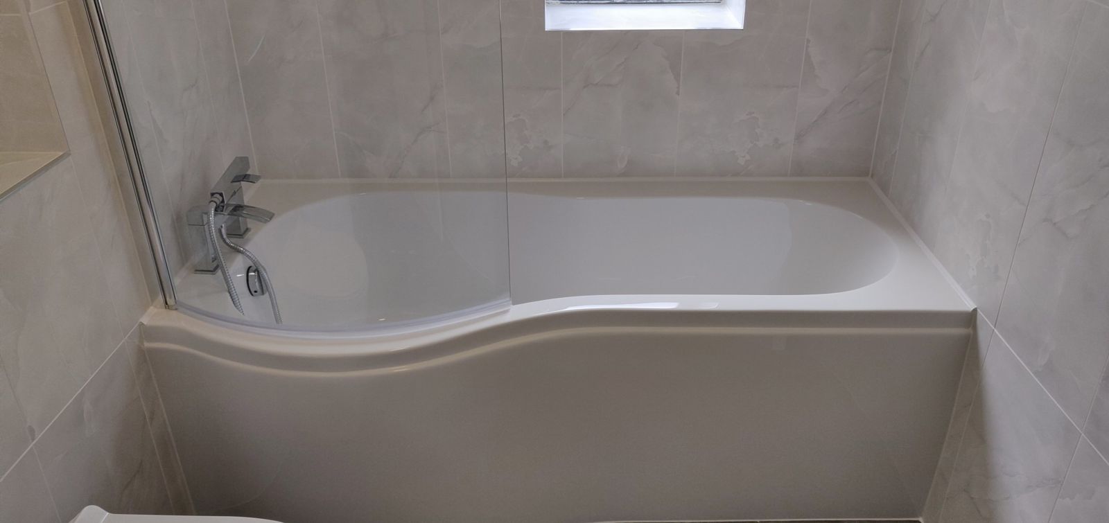 P-shaped bath with chrome mixer and glass screen in the refitted bathroom