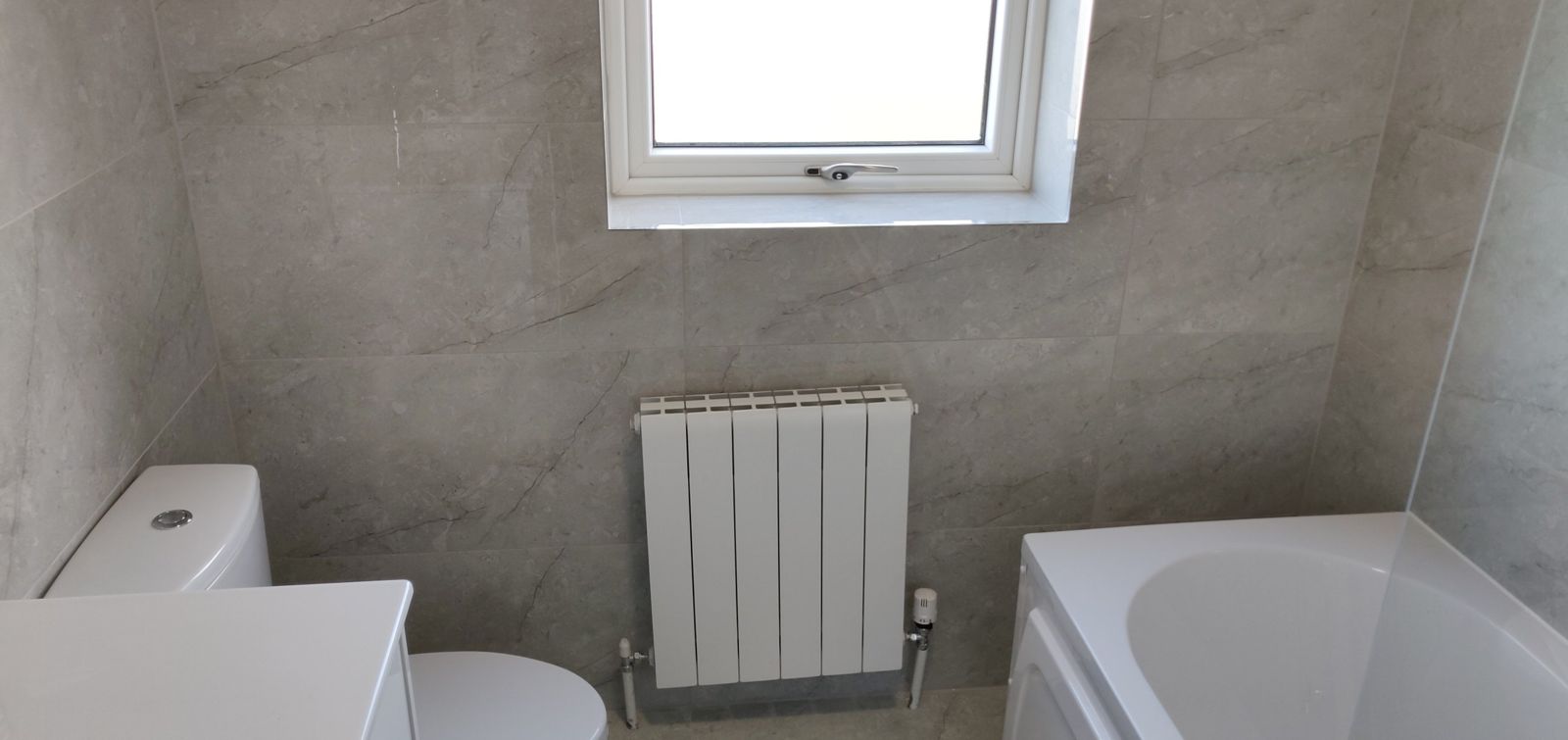 Tiled wall with new designer radiator under the window