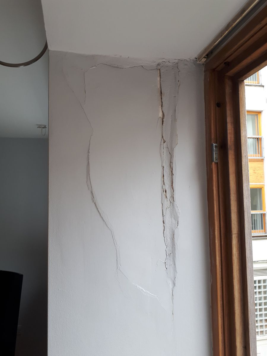 Large cracks in the wall beside a window